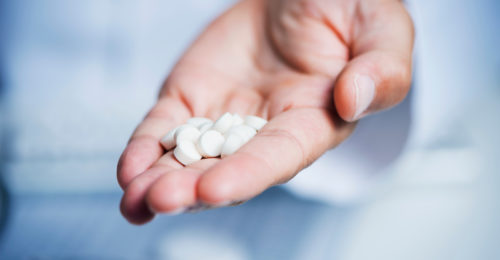 stock-photo-closeup-of-a-caucasian-doctor-man-in-a-white-coat-giving-some-pills-to-the-observer-1387453166